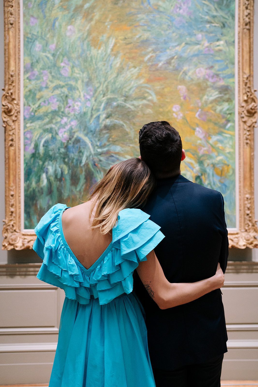 Couple leaning against each other looking into a painting at an art museum